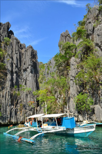 Boat beside tall cliffs in Palawan. Photo by Julie Mae Dado.